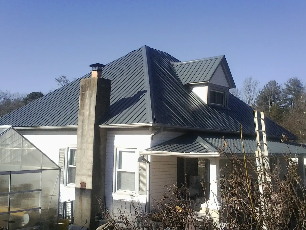 Dark blue standing seam metal roof on a white farmhouse with dormer — Slate & Tile Roof Repair by Roofing Brothers in Bridgton