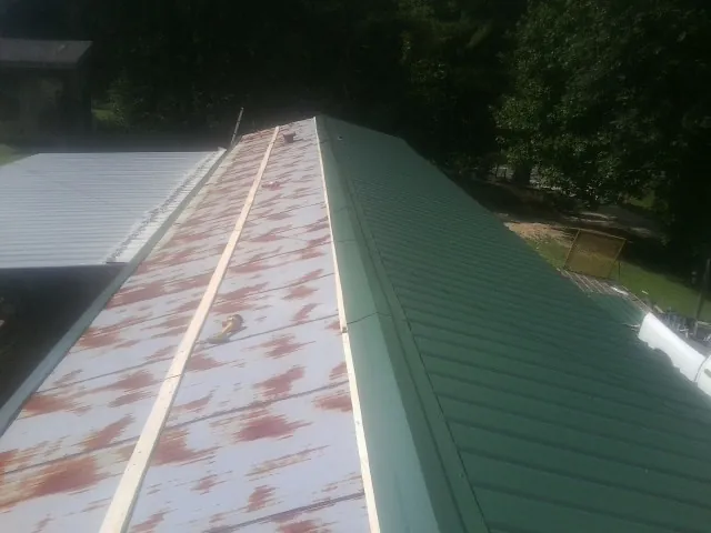 Old rusted panels beside newly installed green metal roofing — Wind Damage Roof Repair by Roofing Brothers in Bridgton