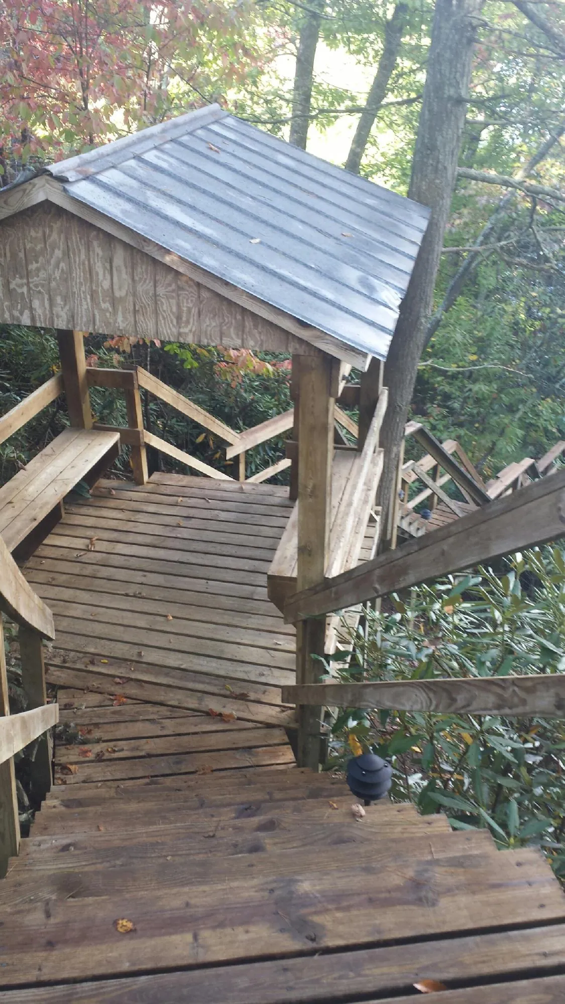 Metal roofed shelter over wooden steps on a wooded walkway — Skylight Repair & Installation work by our crew in Bridgton