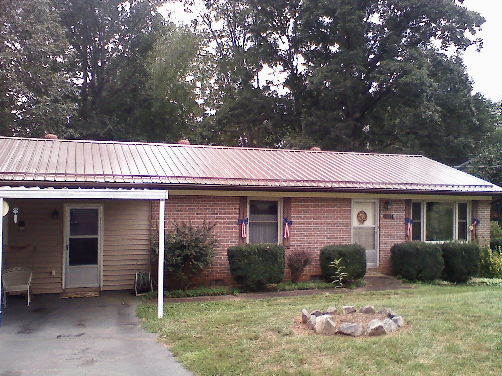 Bronze metal roof and carport on a brick ranch home — Roof Repair work by our crew in Bridgton