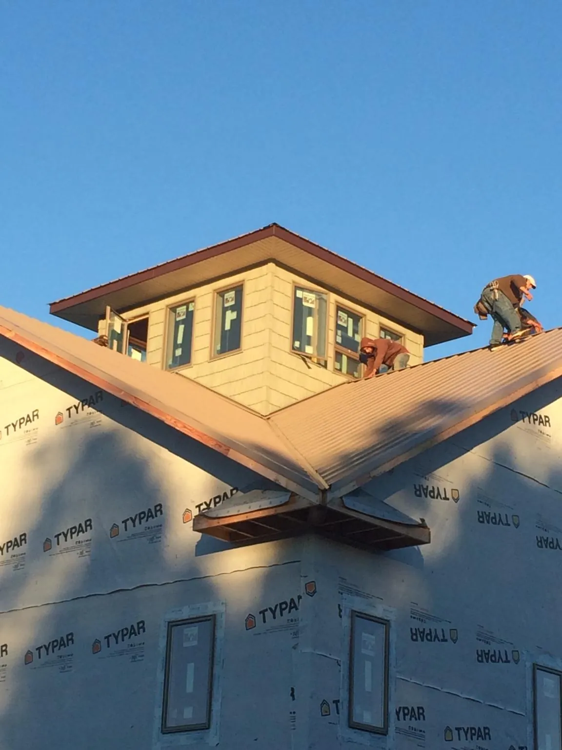 Roofers working around a rooftop cupola on a new metal roof at sunset — Roof Waterproofing in Bridgton by Roofing Brothers